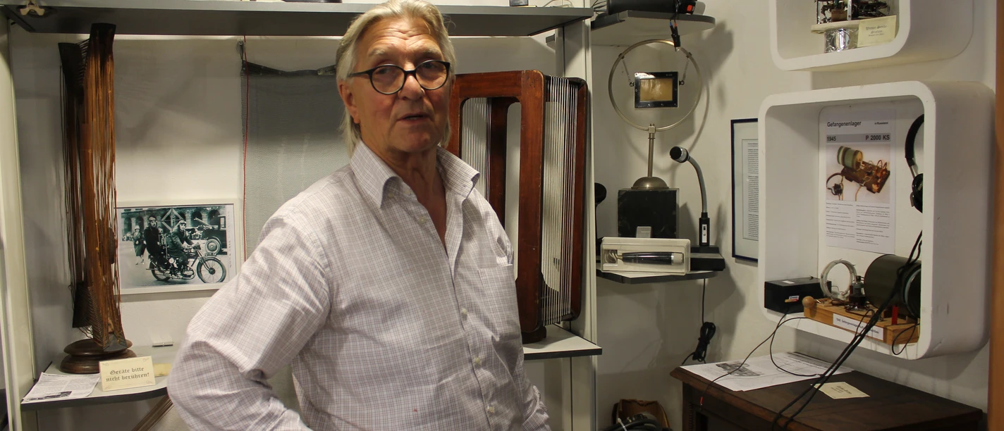 Rudis Rundfunk- und Maler-Museum Ein älterer Mann steht in einem Ausstellungsraum mit historischen Rundfunkgeräten und Technikexponaten.