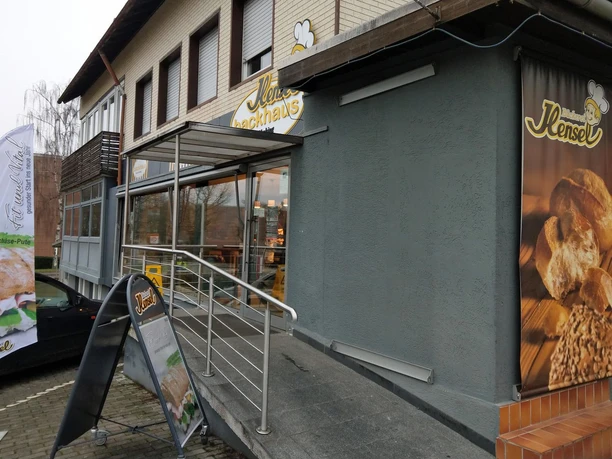 Eingang der Bäckerei Hensel mit Rampe, Schaufenster und Werbeschildern