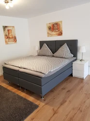 Helles Schlafzimmer mit Doppelbett, modernem Design, Holzfußboden und zwei Nachttischen mit Lampen.