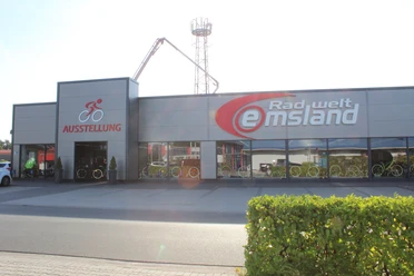 Radwelt Emsland Modernes Fahrradgeschäft mit großer Glasfassade, Ausstellung von Fahrrädern und rotem Firmenlogo.