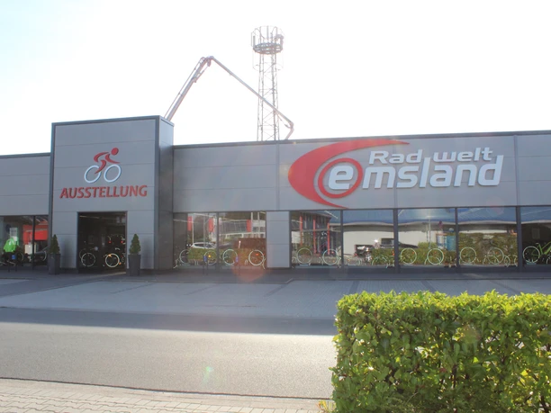 Radwelt Emsland Modernes Fahrradgeschäft mit großer Glasfassade, Ausstellung von Fahrrädern und rotem Firmenlogo.