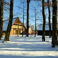 schnee-bauernhaus Historisches Bauernhaus mit Reetdach im Schnee zwischen winterlichen Bäumen und blauem Himmel