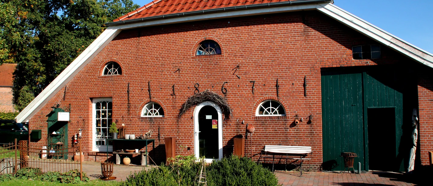 A red brick building, the Gockenhaus, with a red-tiled roof, a green door, and several small windows; in front of it is a garden with shrubs and a lawn