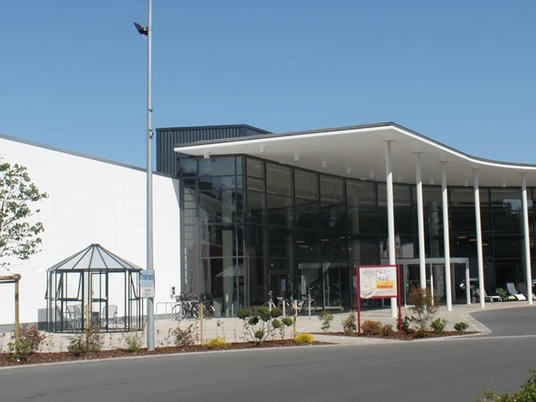 Möbel Eilers Es wird der Eingangsbereich eines großen Möbelhauses in der Gemeinde Apen angezeigt. Rechts sieht man einige Parkplätze