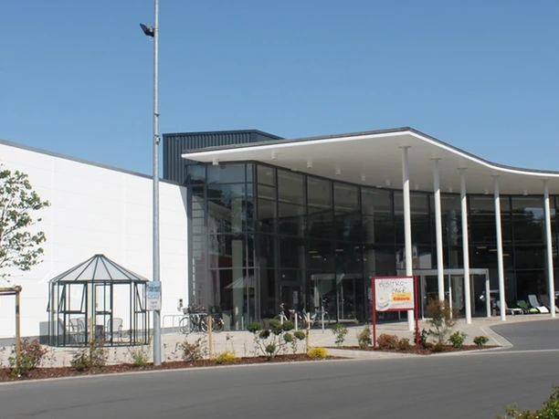 Möbel Eilers Es wird der Eingangsbereich eines großen Möbelhauses in der Gemeinde Apen angezeigt. Rechts sieht man einige Parkplätze