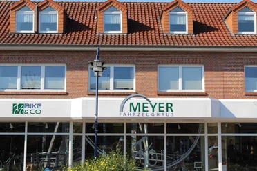 Fahrzeughaus Meyer Backsteingebäude mit rotem Dach und Schaufensterfront des Fahrzeughaus Meyer in Papenburg