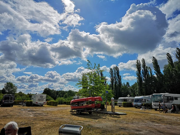Paddel- und Pedal Rhauderfehn, Ostfriesland Wohnmobile und Wohnwagen auf einem Reisemobilstellplatz unter einem bewölkten Himmel mit blauem Hintergrund