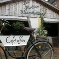 De Holter Wienkeller Fahrrad mit Schild Café offen vor Eingang zu 'De Holter Wienkeller', einem rustikalen Gebäude mit Holzfassade