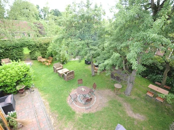 De Holter Wienkeller, Außenbereich, Erholungsort Rhauderfehn5 Garten mit mehreren Sitzbereichen aus Holzstühlen und Tischen, umgeben von Bäumen und Hecken