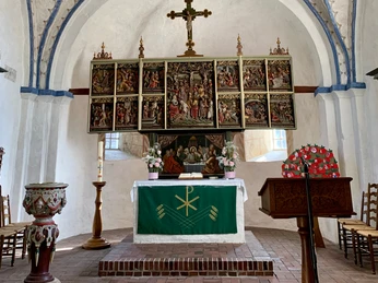 Ein prächtiger Altar mit zahlreichen biblischen Szenen im Inneren einer Kirche, im Zentrum ein Kreuz.