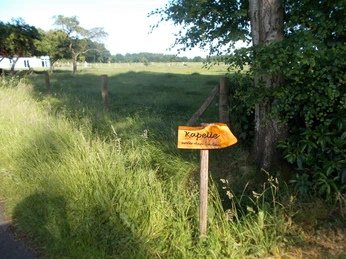 Kapelle "Unter den Linden" Wegweiser Der Wegweiser zeigt zur "Kapelle unter den Linden", umgeben von Wiese und Bäumen. Ein ruhiger Pfad führt entlang.