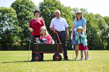 Familie beim Swingolf Eine glückliche Familie, inkl. Kinder und Senioren, genießt Swingolf auf einer grünen Wiese im Sommer.