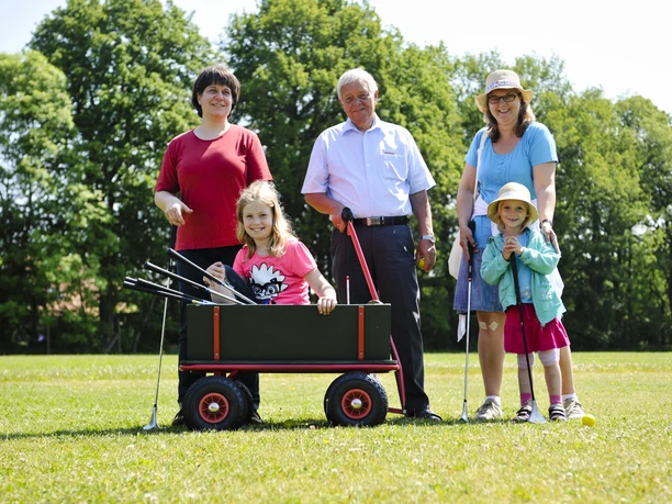Familie beim Swingolf Eine glückliche Familie, inkl. Kinder und Senioren, genießt Swingolf auf einer grünen Wiese im Sommer.
