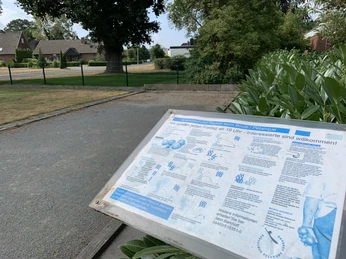 Boulebahn Hof Kleiberg Eine Boulebahn umgeben von grüner Natur und einer Informationsschild im Vordergrund.