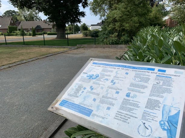 Boulebahn Hof Kleiberg Eine Boulebahn umgeben von grüner Natur und einer Informationsschild im Vordergrund.