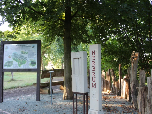 herbrumer-naturgarten-03-emsland-tourismus-christina-poll_mini Holzskulpturen und Informationstafel im schattigen Bereich des Herbrumer Naturgartens.