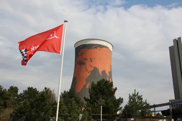 Funpark Meppen Roter Kühlturm mit Weltkartenmotiv hinter wehender roter Flagge im Freizeitpark in Meppen.
