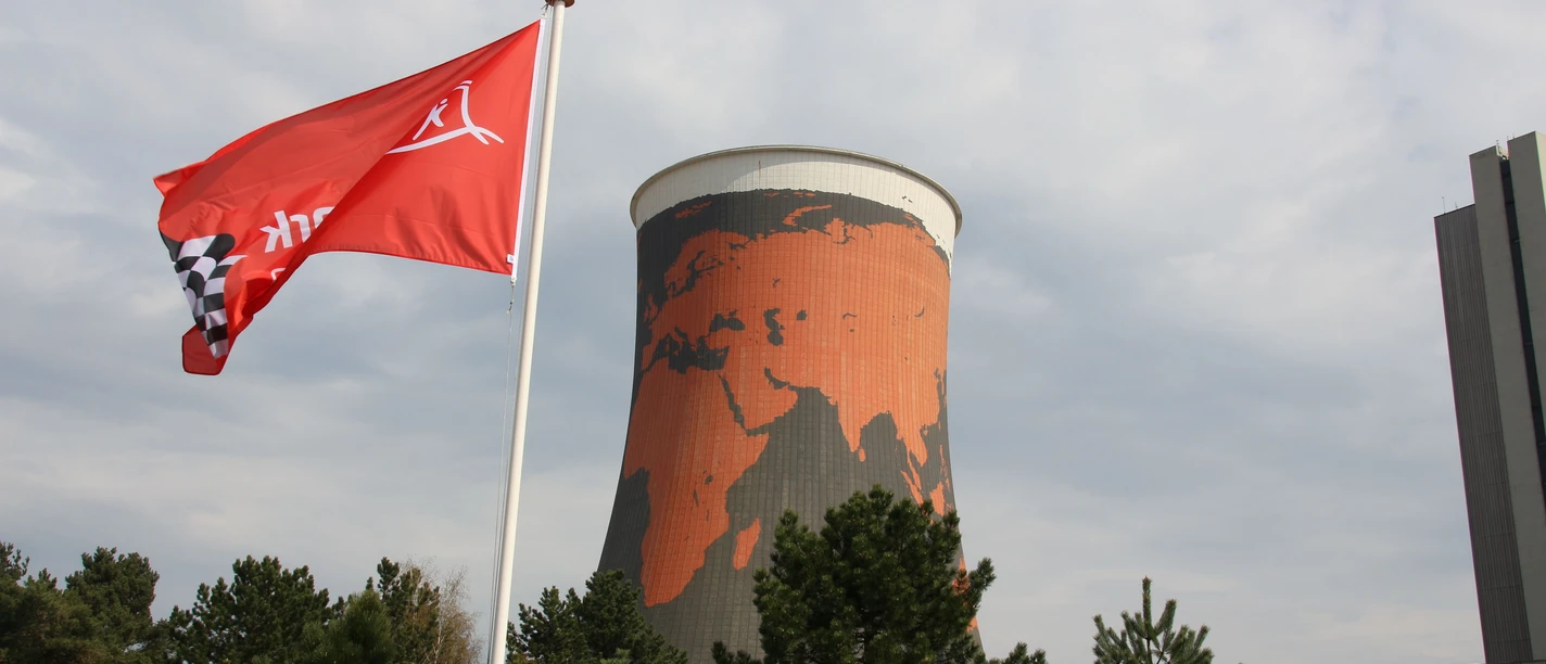 Funpark Meppen Roter Kühlturm mit Weltkartenmotiv hinter wehender roter Flagge im Freizeitpark in Meppen.