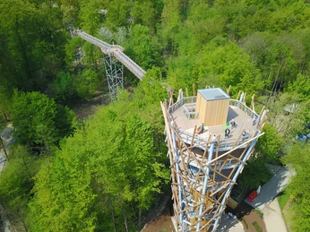 Baumwipfelpfad Bad Iburg Aussichtsturm aus Holz in einem dichten, grünen Wald mit Besucherplattform und Gehweg.Wooden observation tower in a dense, green forest with visitor platform and walkway.Udsigtstårn i træ i en tæt, grøn skov med besøgsplatform og gangbro.Houten uitkijktoren in een dicht, groen bos met bezoekersplatform en loopbrug.