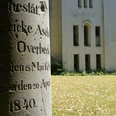 hx-petrikirche-thomashampel alter Grabstein mit unleserlicher Inschrift auf Friedhofswall