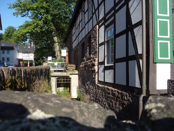 Mit Bruchsteinen eingefasster Grubekanal mit Fachwerkhaus am rechten Bildrand