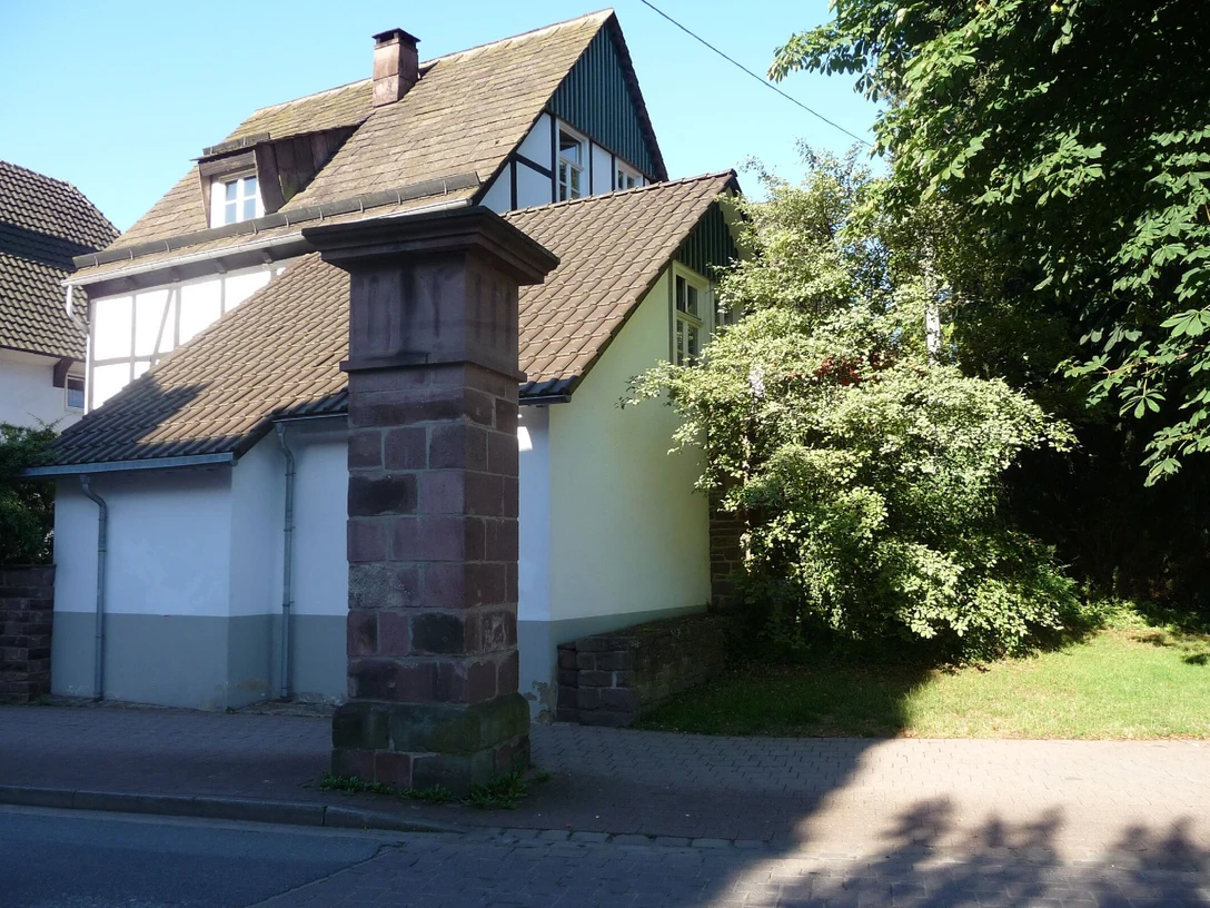 Sandsteinpfeiler mit Haus im Hintergrund
