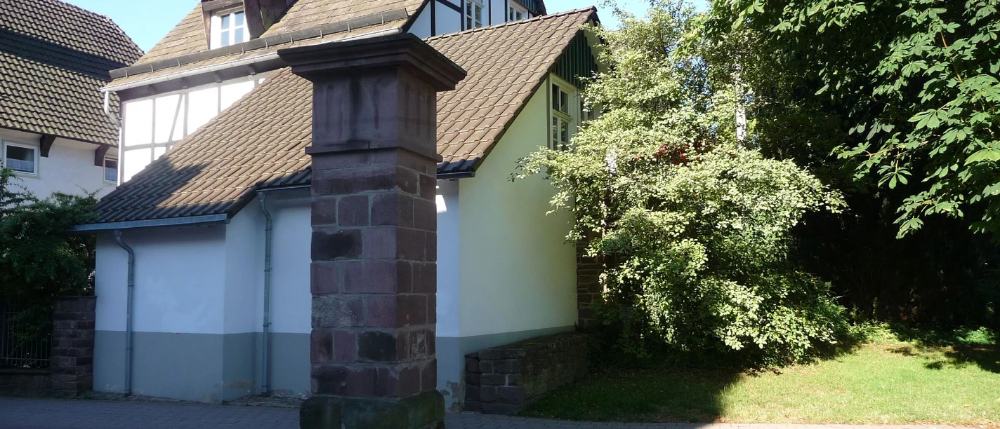 Sandsteinpfeiler mit Haus im Hintergrund