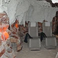 sitzplaetze-salzgrotte Eine Salzgrotte mit zwei Liegestühlen, umgeben von salzbedeckten Wänden und gedämpfter Beleuchtung.