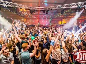 Partyszene_Disco Tange Eine lebendige Partyszene in einer Disco gefüllt mit jubelnden Menschen unter bunten Lichtern.