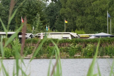 Mobilheime am Campingplatz Mobilheime an einem idyllischen Campingplatz, umgeben von grünen Bäumen und Wasser, Fahnen wehen im Wind.
