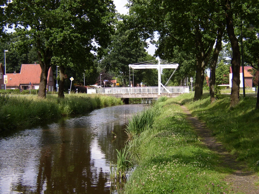 Augustfehn Kanal mit Treidelpfad Ein idyllischer Kanal fließt unter einer modernen Fußgängerbrücke, begleitet von einem erholsamen Treidelpfad und gesäumt von Bäumen. Der Augustfehn Kanal bietet eine malerische Kulisse für Spaziergänger und Naturliebhaber.