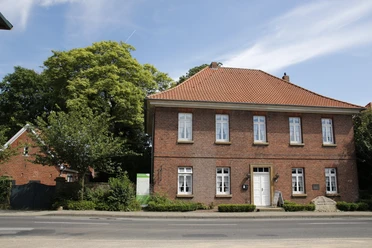 Handwerker-Museum im Heimathaus Freren Zweigeschossiges Backsteinhaus mit rotem Ziegeldach und weißen Fenstern, umgeben von Bäumen.