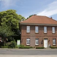 Handwerker-Museum im Heimathaus Freren Zweigeschossiges Backsteinhaus mit rotem Ziegeldach und weißen Fenstern, umgeben von Bäumen.
