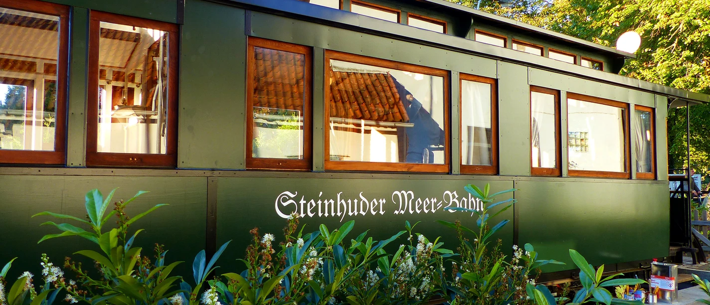 Ein dunkelgrüner Waggon mit großen Fenstern zeigt den Schriftzug „Steinhuder Meer Bahn“.