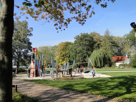 Spielplatz im Park Ein weitläufiger Spielplatz mit modernen Kletteranlagen, umgeben von Bäumen im Park.