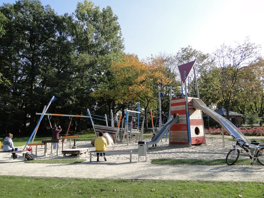Spielgeräte auf dem Spielplatz im Park Verschiedene bunte und moderne Spielgeräte auf einem Sandspielplatz, umgeben von Grünflächen.