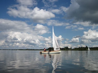 Segelboot auf dem Steinhuder Meer Ein elegantes Segelboot gleitet über das ruhige Wasser des Steinhuder Meers unter einem Himmel voller Wolken.