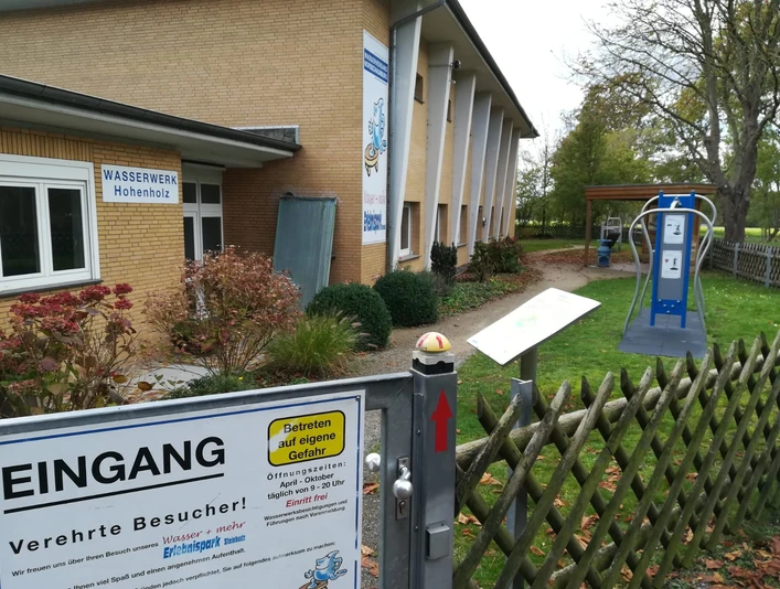 Wasser + mehr Erlebnispark Eingang Im Vordergrund ist der Eingang des Wasser + mehr Erlebnisparks in Hohenholz zu sehen. Ein Schild informiert über den Zugang.