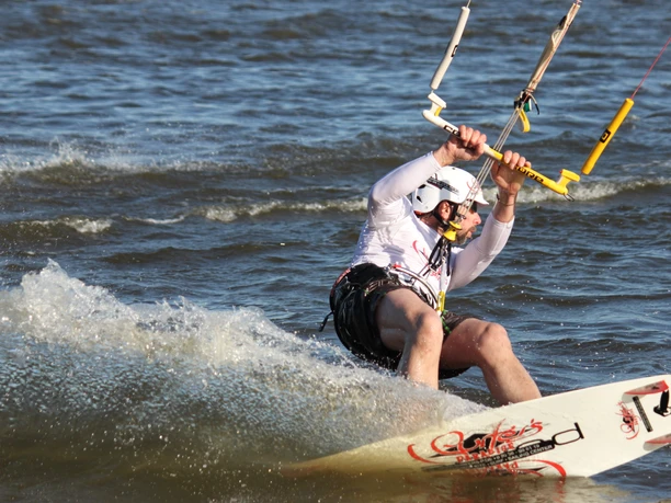 Surfers Paradise Ein Kitesurfer in Aktion auf der Nordsee, die Gischt spritzend hinter ihm aufwirbelnd.