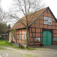 Museum Mardorf Fachwerkhof im Grünen, mit rotem Backstein und blauem Tor; umgeben von Bäumen und Bänken.