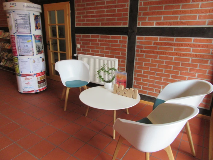 Sitzecke im Haus des Gastes Helle, moderne Sitzecke mit weißen Sesseln und Tisch auf rotem Fliesenboden in einem öffentlichen Raum.Bright, modern seating area with white armchairs and table on a red tiled floor in a public space.Lyst, moderne opholdsområde med hvide lænestole og bord på et rødt klinkegulv i et offentligt rum.Lichte, moderne zithoek met witte fauteuils en tafel op een rode tegelvloer in een openbare ruimte.