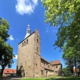 Stiftskirche in Wunstorf Stiftskirche Wunstorf, romanischer Baustil, charakteristischer Turm aus Sandstein, umgeben von Bäumen.
