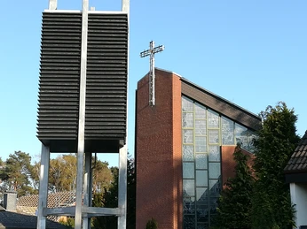 Blick auf die St. Hedwig Kirche Steinhude Backstein-Kirche unter blauem Himmel, markantes Glockenspiel aus silberfarbenen Lamellen im Vordergrund.