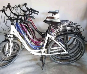 Fahrradverleih Nülle Mehrere Stadtfahrräder stehen geordnet nebeneinander auf einem Betonboden in einem Fahrradverleih.
