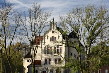 neustadt-amtsgericht Ein historisches Gebäude mit verzierten Fenstern und Turmspitze, umrahmt von Bäumen im Herbst.