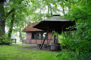 Grillhütte Dudensen Grillhütte Dudensen aus roten Ziegeln mit Walmdach, umgeben von dichtem Laubwald und grünem Rasen.