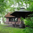 Grillhütte Dudensen Grillhütte Dudensen aus roten Ziegeln mit Walmdach, umgeben von dichtem Laubwald und grünem Rasen.