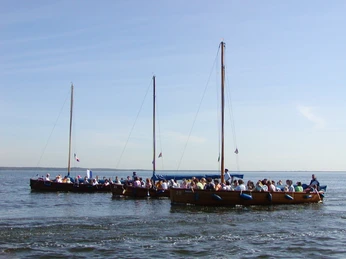 Auswanderer Drei volle Boote segeln gemeinsam auf einem ruhigen See unter einem klaren, blauen Himmel.Three full boats sailing together on a calm lake under a clear blue sky.Tre fyldte både sejler sammen på en rolig sø under en klar blå himmel.Drie volle boten varen samen op een kalm meer onder een strakblauwe hemel.