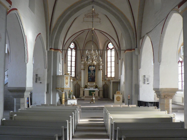 Altar Liebfrauenkirche Blick in eine helle Kirche mit weißem Gewölbe, hölzernen Bänken und kunstvollem Altarbild.