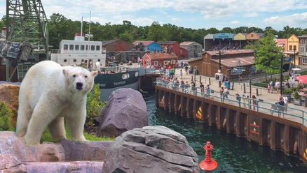 Erlebnis Zoo Hannover Eisbär im Zoo Hannover, vor Kulisse eines Hafenviertels mit bunten Gebäuden und einem Schiff.